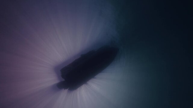 contraluz desde el fondo del mar hacia un bote con buzos que se tiran al agua para iniciar su actividad