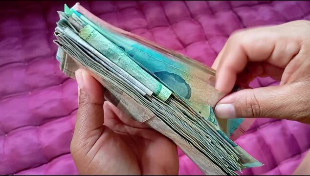 woman's hand counting rupiah banknotes