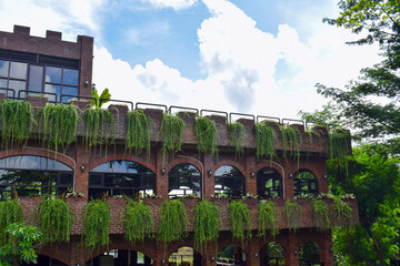 A building with castle-like architecture with exposed brick walls, with vines hanging from the balcony