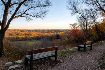Obraz premium Serene Autumn Vista: Two Benches Overlooking a Breathtaking Fall Foliage Landscape