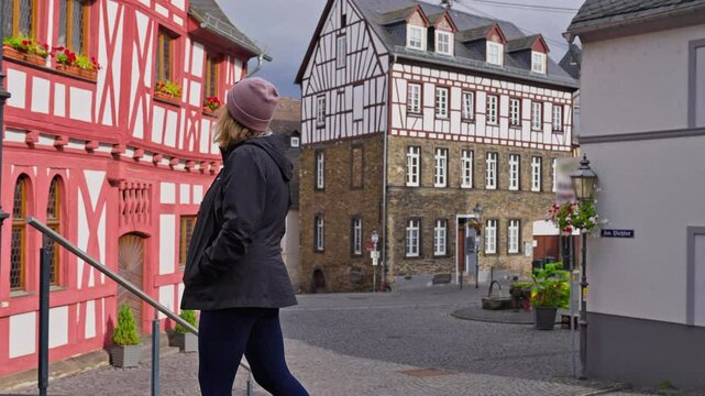 Following a tourist exploring old town square of Rhens, with picturesque medieval half timbered and stone buildings with tracking movement, Rhine River Valley, Germany
