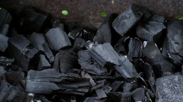 Dark charcoal gradually igniting in barbecue grill, producing glowing red embers and generating intense heat for outdoor cooking preparation