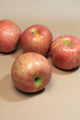 apples on a beige background. It's a sweet, crunchy apple that's shiny and fresh. This is a close-up photo.