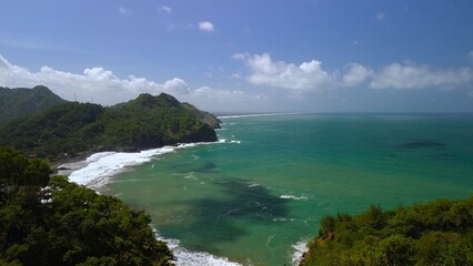 Bird eye view View of the coastline with hills and trees, cliffs, coral reefs and waves from the...