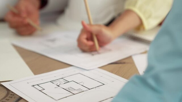 Architect and safety engineer discussion about building blueprint displaying on laptop on table with architectural document and wooden block scatter around at modern office. Closeup. Delineation.