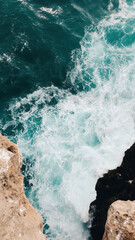 Obraz premium image captures stunning cliffside view of ocean, showcasing crashing waves against rocky formations. vibrant turquoise water contrasts beautifully with rugged coastline, creating serene yet
