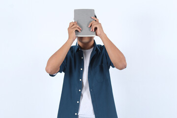 Adult Asian Man Holds Book Covering Face, Expressing Introversion, Shyness, or a Desire