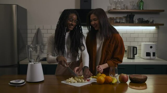 Lesbian multiracial couple in casual clothes are feeding each other and showing love in a modern kitchen at home.