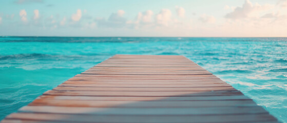 Fototapeta premium wooden pier stretching over turquoise ocean under serene sky creates tranquil atmosphere. gentle waves and soft clouds enhance peaceful scene