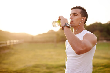 Fitness music, man and drinking water outdoor for health, body wellness and relax on sports break. Headphones, thirsty runner and bottle for hydration, electrolytes and liquid nutrition at sunset