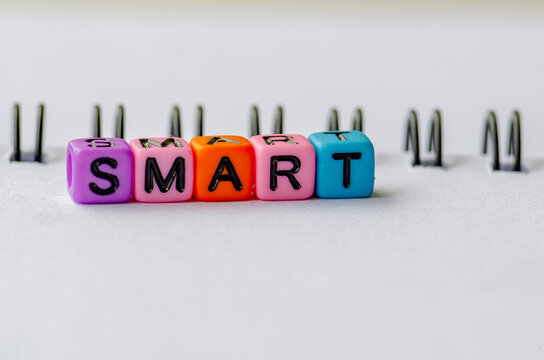 SMART text on colorful plastic beads representing Specific, Measurable, Achievable, Relevant and Time Bound with notepad background