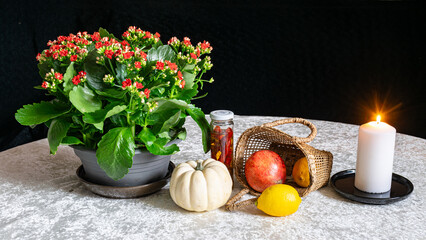 still life on white tablecloth, burning candle, bright flower and other objects