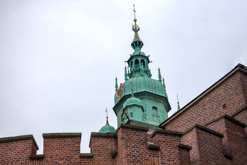 
an impressive green-roofed church tower with a golden spire rising against a cloudy sky.