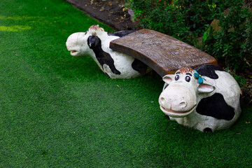 Statue cow chair on green grass in park with copy space