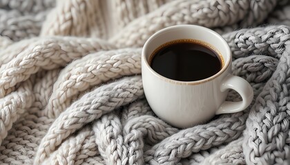 Obraz premium Warm coffee in a mug on a knitted blanket.