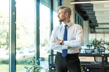 Fototapeta premium Handsome young businessman standing in modern office