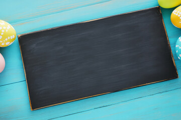 Blackboard with Easter eggs on wooden surface.