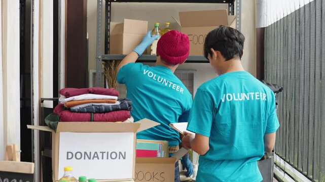 Young volunteers preparing supplies for food donation program. Male teens take notes and organizing groceries for charity. Volunteering, social aid, donations, food bank, charity