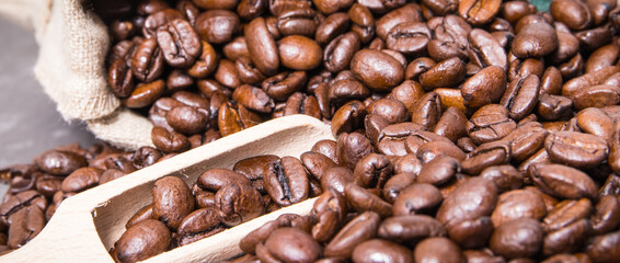 Heap of dark roasted fragrant coffee beans in jute bag