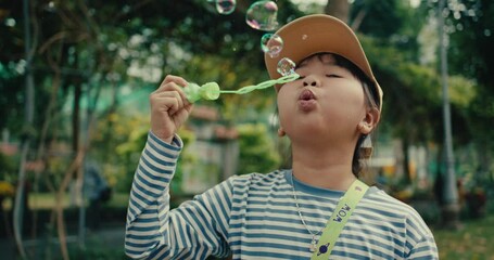 Smiling child blowing bubbles in a park on a sunny day, joyful and carefree vibe