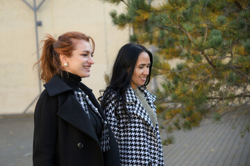 Fototapeta premium Women walking on a street adorned with autumn foliage in a vibrant urban setting