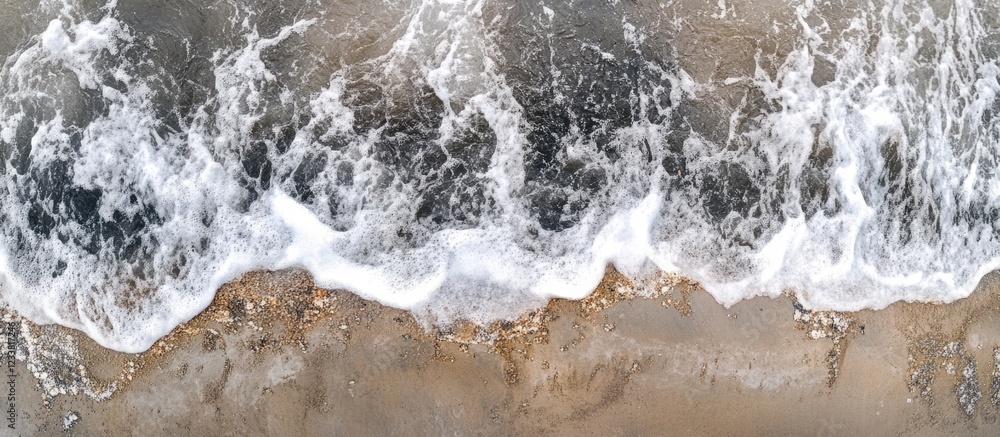 Poster Aerial view of ocean waves crashing on sandy beach with foam and wet sand Copy Space