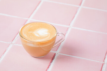 A cup of cappuccino coffee on pink tile background