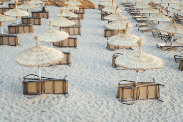 parasols et chaises longues alignés sur une plage de sable fin à Majorque, Baléares. Ambiance de fin de saison. Absence de touristes. Vacances à la montagne. Plages désertes. Parasols végétaux transat