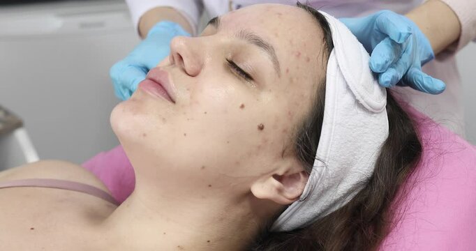 People, beauty, spa, cosmetology and technology concept - Cosmetologist makes the procedure microcurrent therapy of the facial skin of a beautiful, young woman in a beauty salon