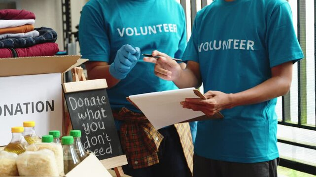 Volunteers checking and preparing boxes of food supplies for donation. Teen partners working together to help the needy. Charity, donation concept, teamwork, social help, food drive