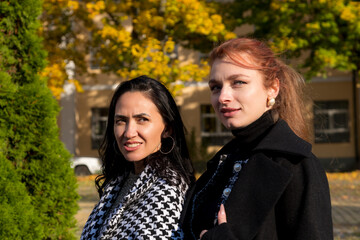 Fototapeta premium Stylish women enjoying a sunny autumn day while walking down the street