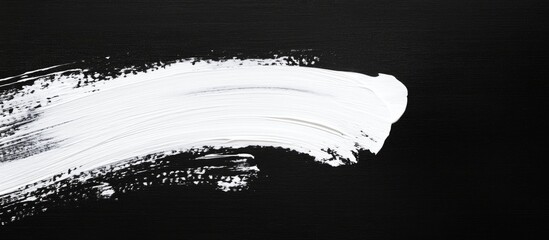 White paint brush stroke on black canvas creating a blank space for text or design elements for artistic presentations and backgrounds