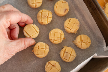 A hand places a scone on the baking sheet.