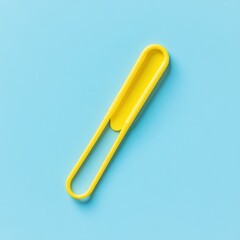 Obraz premium Yellow plastic clip on blue background, simple office supply