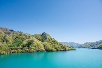 Obraz premium 木々の深緑とエメラルドグリーンの水面が美しい八ッ場ダムのあがつま湖