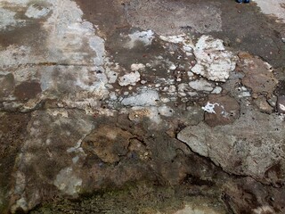 The weathered concrete pavement has many cracks and breaks into irregular pieces.