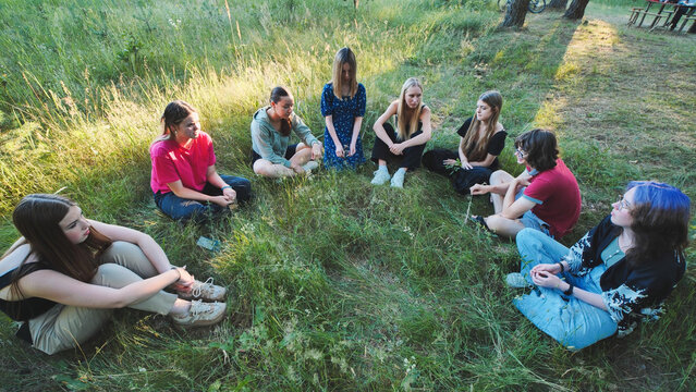 Graduates celebrating together, sitting in grassy circle, sharing joy and memories after graduation milestone - Powered by Adobe