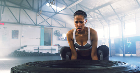 Fitness, woman and tire in gym for workout, intense training and weightlifting exercise. Girl...