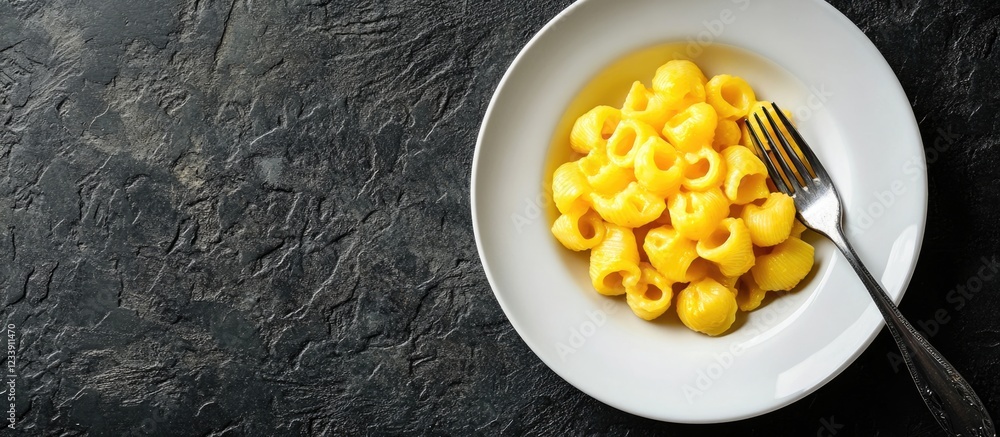 Poster plate of mac and cheese pasta with fork on dark textured background and copy space for text