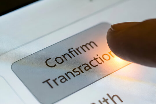 Cryptocurrency Trading, A close-up of a finger pressing the "Confirm Transaction" button on a digital screen, indicating a financial action. - Powered by Adobe