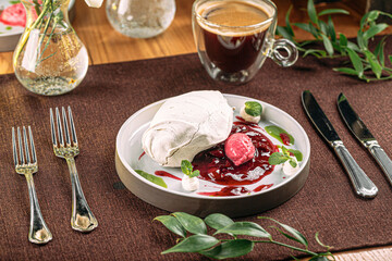 Portion of gourmet Pavlova dessert with berry mousse and jam