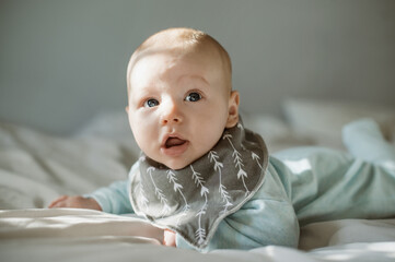 Cute, adorable and portrait of a baby on a bed relaxing, resting and laying after playing. Young, innocent and little boy infant or newborn child lying in his nursery or bedroom in the modern house.