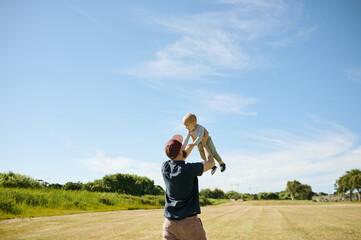 Happy family, park and father lifting baby in field for bonding, quality time and adventure in nature. Childhood, love and dad carrying child playing outdoors on holiday, summer vacation and weekend