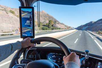 View from inside the cabin of a truck showing hands firmly gripping the steering wheel as the...