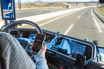 Truck driver driving on a highway while holding a phone in his hand, despite it being prohibited by...