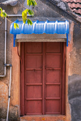 A vibrant red wooden door with a blue signboard, representing the charm of old Indian village homes.