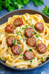 Fototapeta premium Creamy italian sausage and fettuccine alfredo pasta sprinkled with parsley