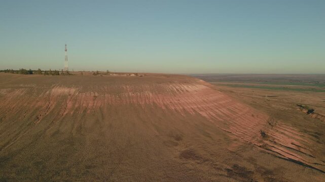 Eroded hilltop dominating flat landscape under clear sky