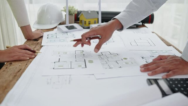 Close up of hands working brainstorming and measuring for cost estimating on paperworks and floor plan drawings about design architectural and engineering for houses and buildings.