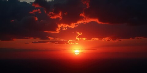 Fototapeta premium Fiery orange and crimson hues dominate the sky, framed by ominous dark clouds. At its heart, the sun glows intensely, casting an enchanting orange light that dances across the horizon